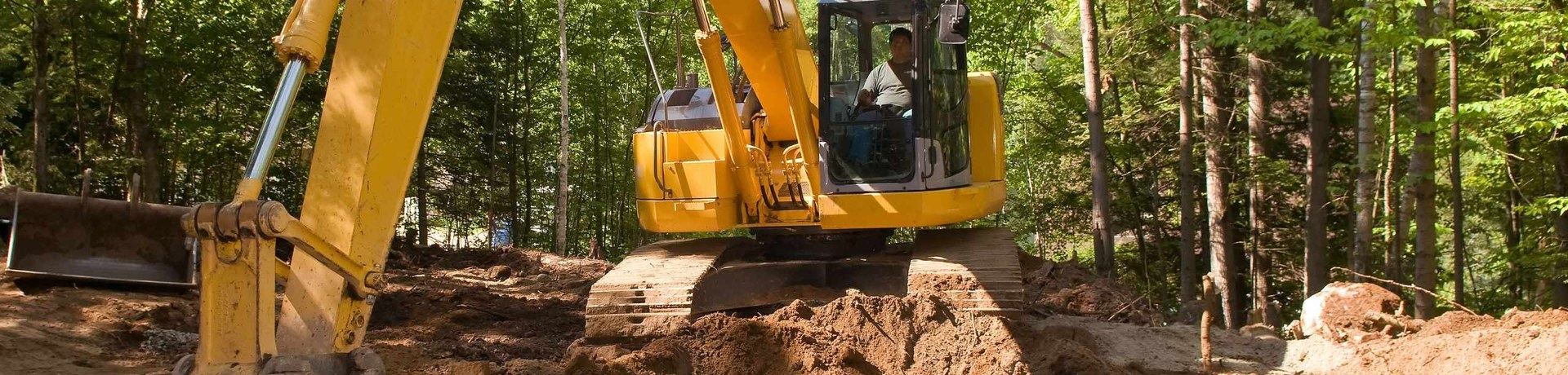 Tracked excavator moving earth on a cleared construction site, operator in the cab