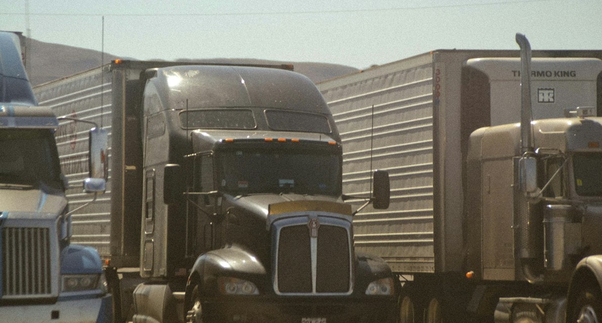 Black semi truck cab parked beside another truck