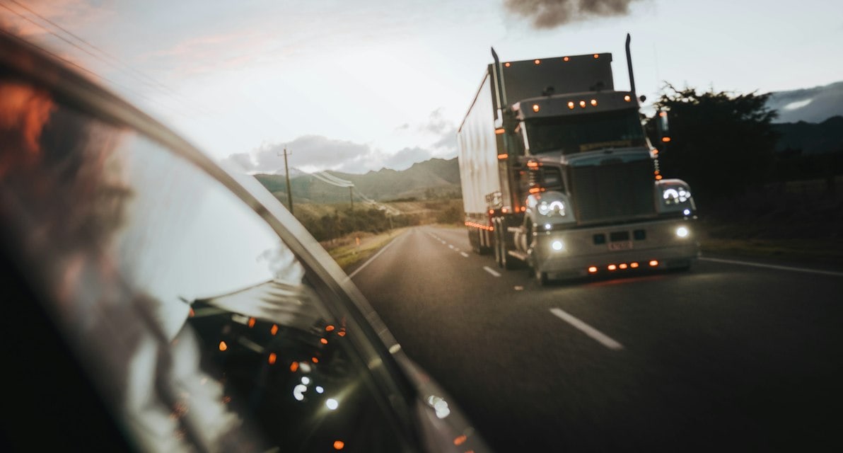 Semi truck driving on a highway under a warm orange sky